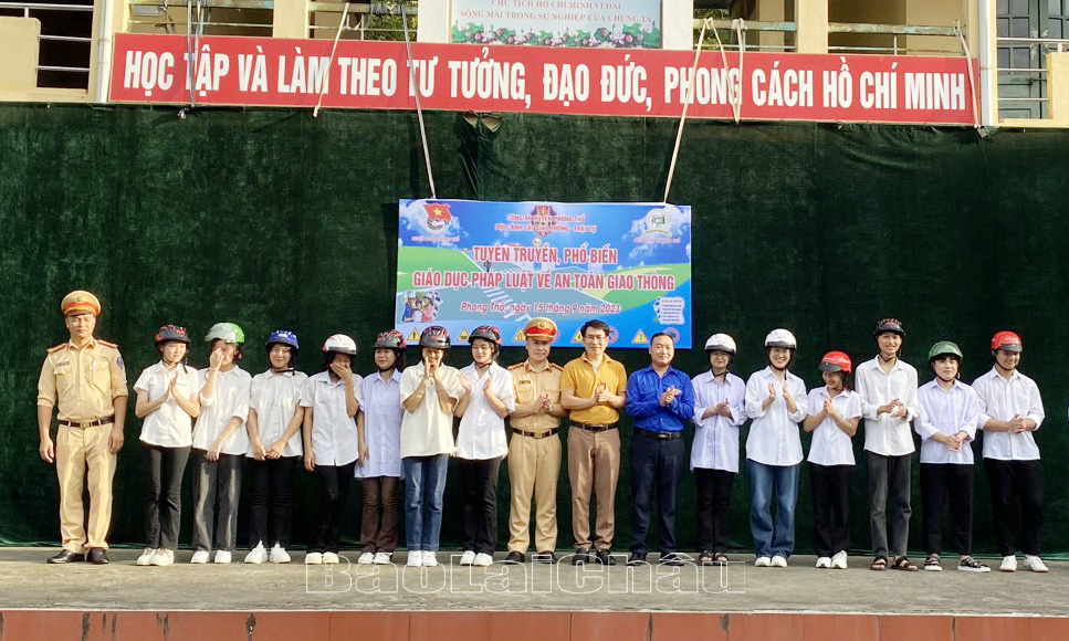 Đại diện Ban giám hiệu Trường THPT Phong Thổ, Huyện đoàn Phong Thổ, Công an huyện Phong Thổ tặng mũ bảo hiểm cho thành viên đội thanh niên xung kích tình nguyện đảm bảo ATGT của trường.